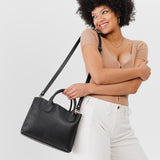 Pebbled--black Large | Model holding mid-size tote purse with  structured leather handles and crossbody strap