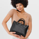 Pebbled--black Large | Model holding mid-size tote purse with  structured leather handles and crossbody strap