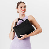 Shadow Black Large | Model holding mid-size tote purse with  structured leather handles and crossbody strap