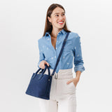 Deep Water Large | Model holding mid-size tote purse with  structured leather handles and crossbody strap