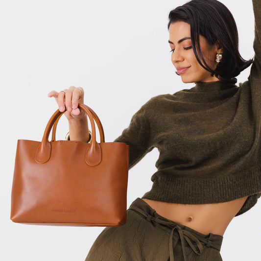 Honey*Large | Model holding mid-size tote purse with  structured leather handles and crossbody strap