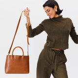 Honey Large | Model holding mid-size tote purse with  structured leather handles and crossbody strap