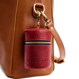 Chili Red | Cylindrical shaped pouch with a gold zipper and swivel lobster claw clasp on a bag