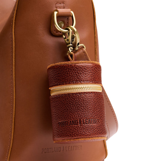 Nutmeg | Cylindrical shaped pouch with a gold zipper and swivel lobster claw clasp on a bag