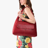 Chili Red Large | A model holding a slouchy triangle shaped shoulder bag with a flap