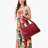 Chili Red Large | A model holding a slouchy triangle shaped shoulder bag with a flap