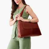 Nutmeg Large | A model holding a slouchy triangle shaped shoulder bag with a flap
