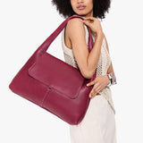Orchid Large | A model holding a slouchy triangle shaped shoulder bag with a flap