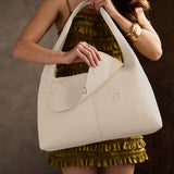 Pebbled Bone Large | A model holding a slouchy triangle shaped shoulder bag with a flap