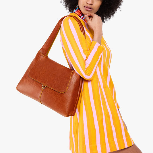 Sienna*Medium | A model holding a slouchy triangle shaped shoulder bag with a flap