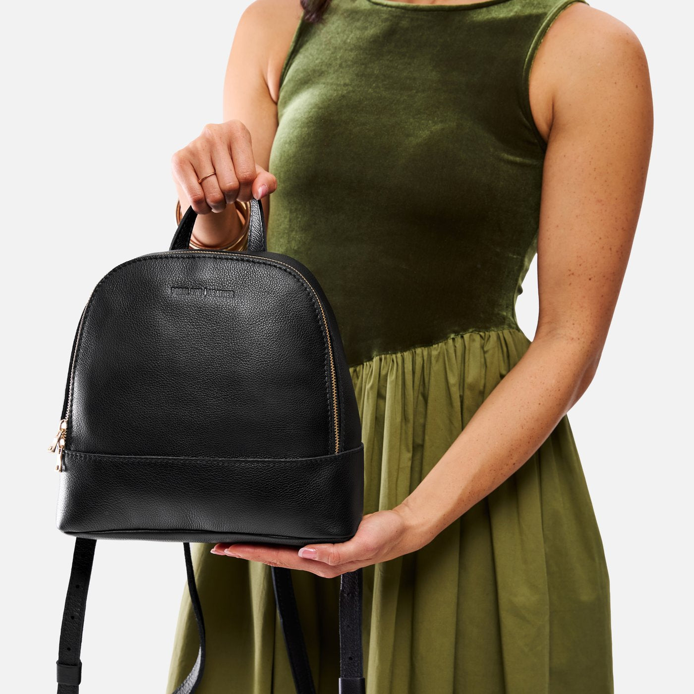 Pebbled--black | Model holding leather backpack with debossed Portland Leather logo on front
