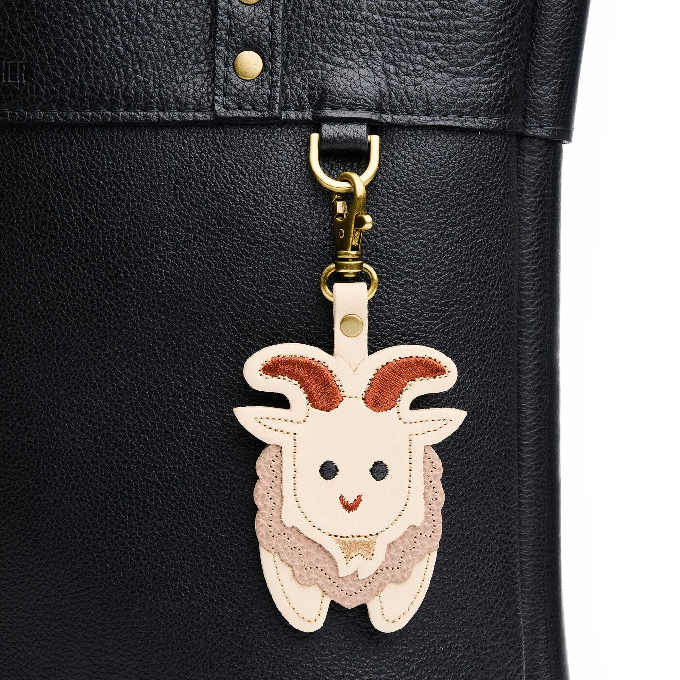 Sawyer | A mountain goat-shaped keychain hanging on a pebbled black bag