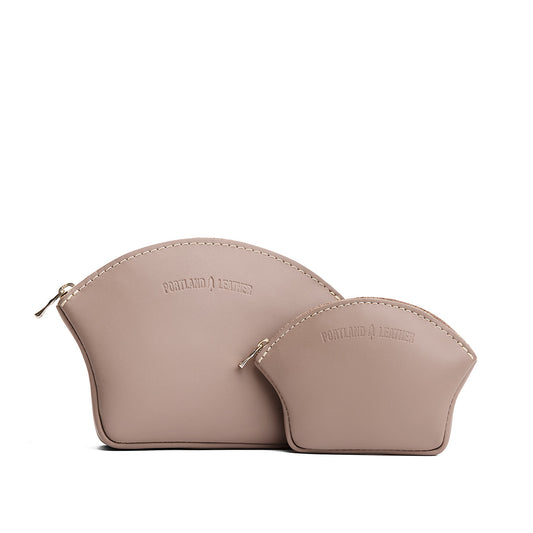 Stone | Comparison shot of small and large seashell shaped leather makeup bags with curved top zipper and flat bottom