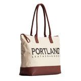 Canvas tote with zipper, leather bottom, and leather handles on a white background