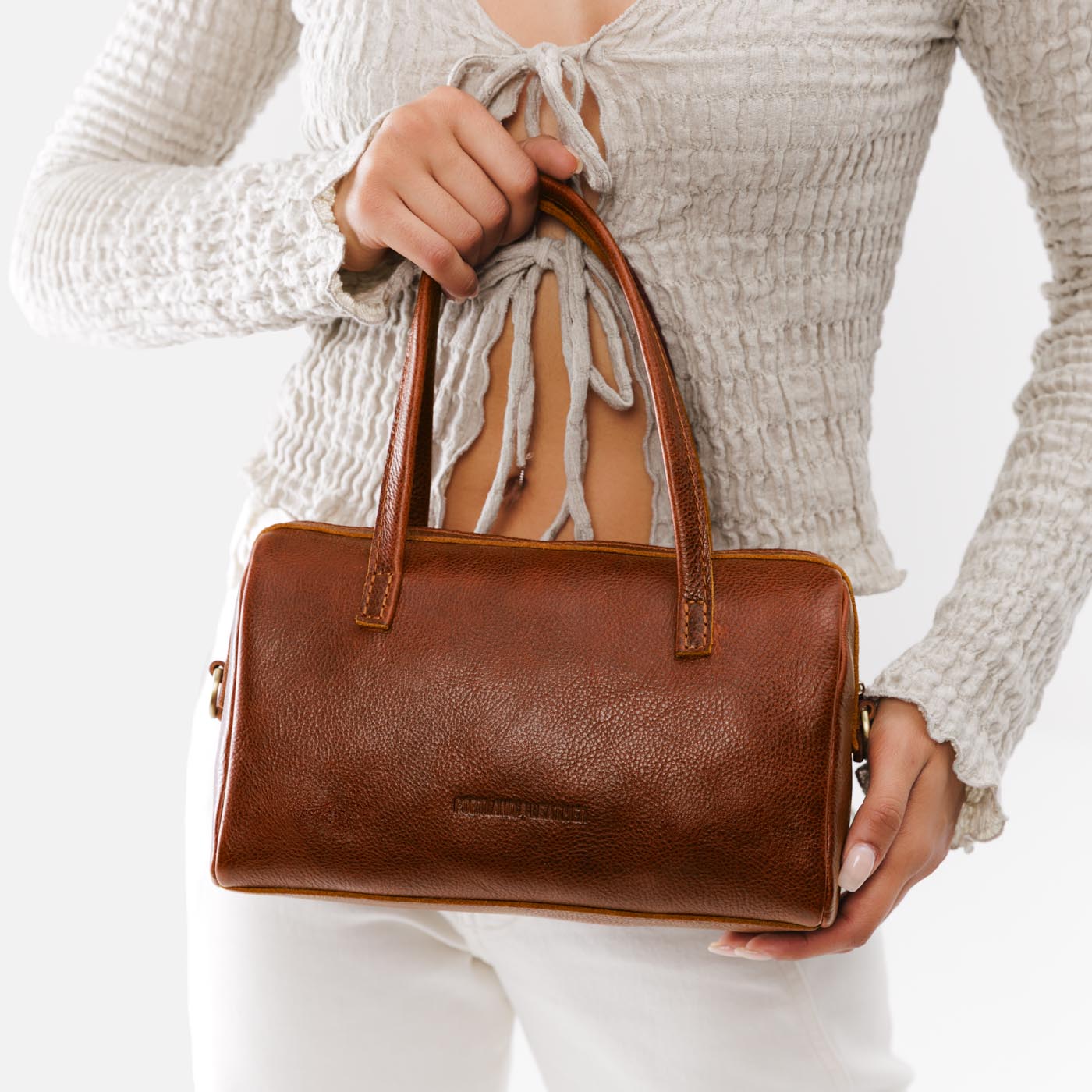 Nutmeg*Large | Model wearing mini duffle shaped handbag with crossbody strap