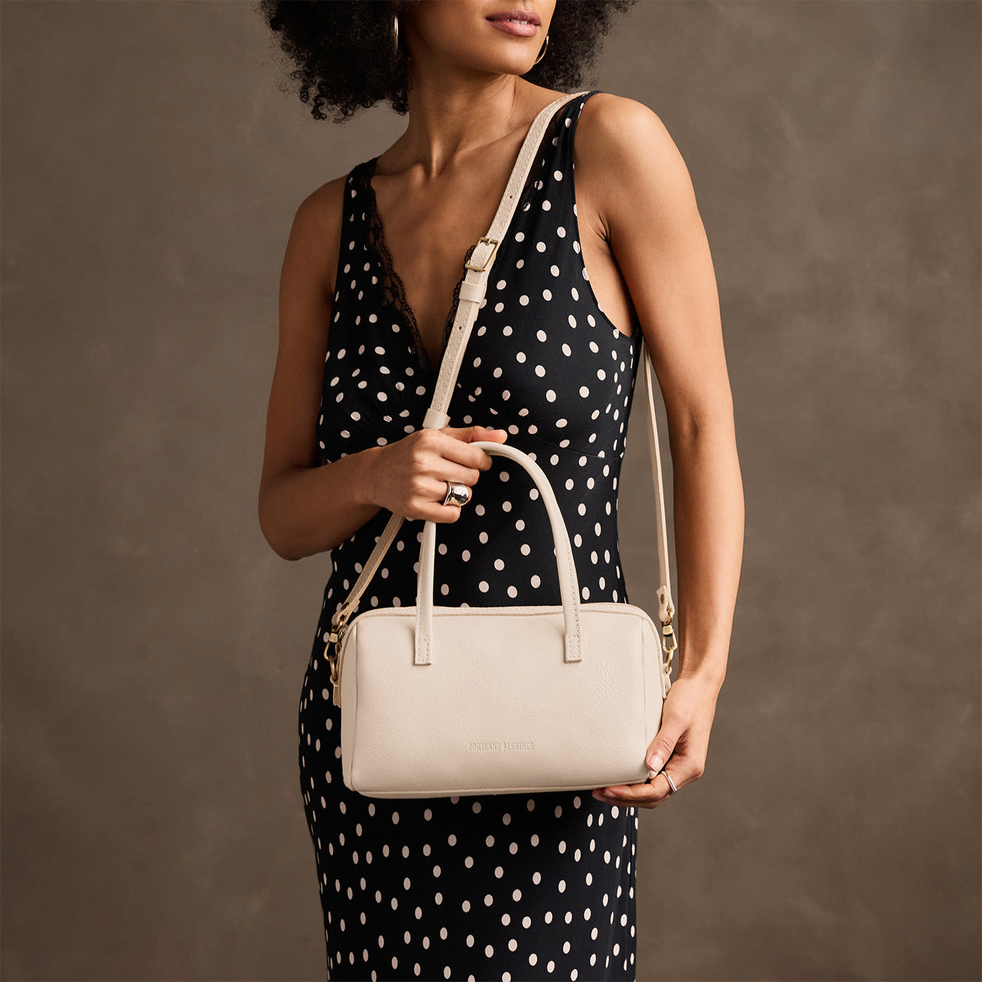 Pebbled Bone*Large | Model holding mini duffle shaped handbag with crossbody strap