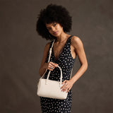 Pebbled Bone Large | Model holding mini duffle shaped handbag with crossbody strap