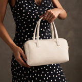 Pebbled Bone Large | Model holding mini duffle shaped handbag with crossbody strap