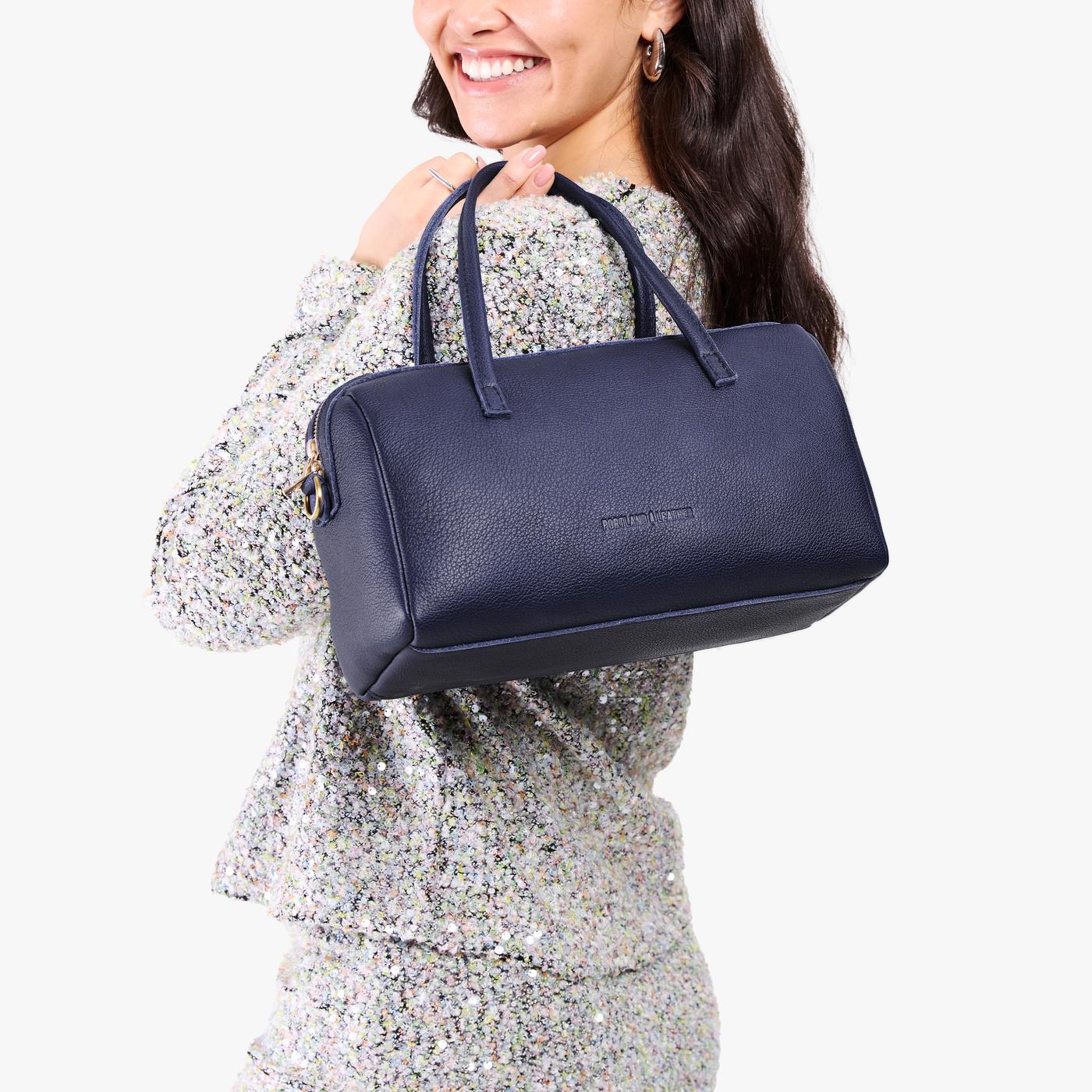 Cobalt*Oversized | Model holding mini duffle shaped handbag with crossbody strap