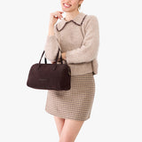 Velvet Brown Oversized | Model holding mini duffle shaped handbag with crossbody strap