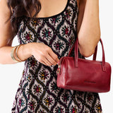 Chili Red Small | Model holding mini duffle shaped handbag with crossbody strap
