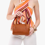 Honey Small | Model holding mini duffle shaped handbag with crossbody strap