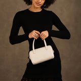 Pebbled Bone Small | Model holding mini duffle shaped handbag with crossbody strap