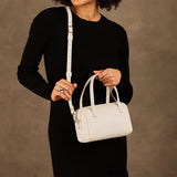 Pebbled Bone Small | Model holding mini duffle shaped handbag with crossbody strap