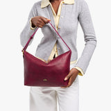 Orchid Large | Model Wearing medium sized slouchy leather shoulder bag with zipper opening and three metal tree emblems