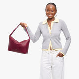 Orchid Large | Model Wearing medium sized slouchy leather shoulder bag with zipper opening and three metal tree emblems
