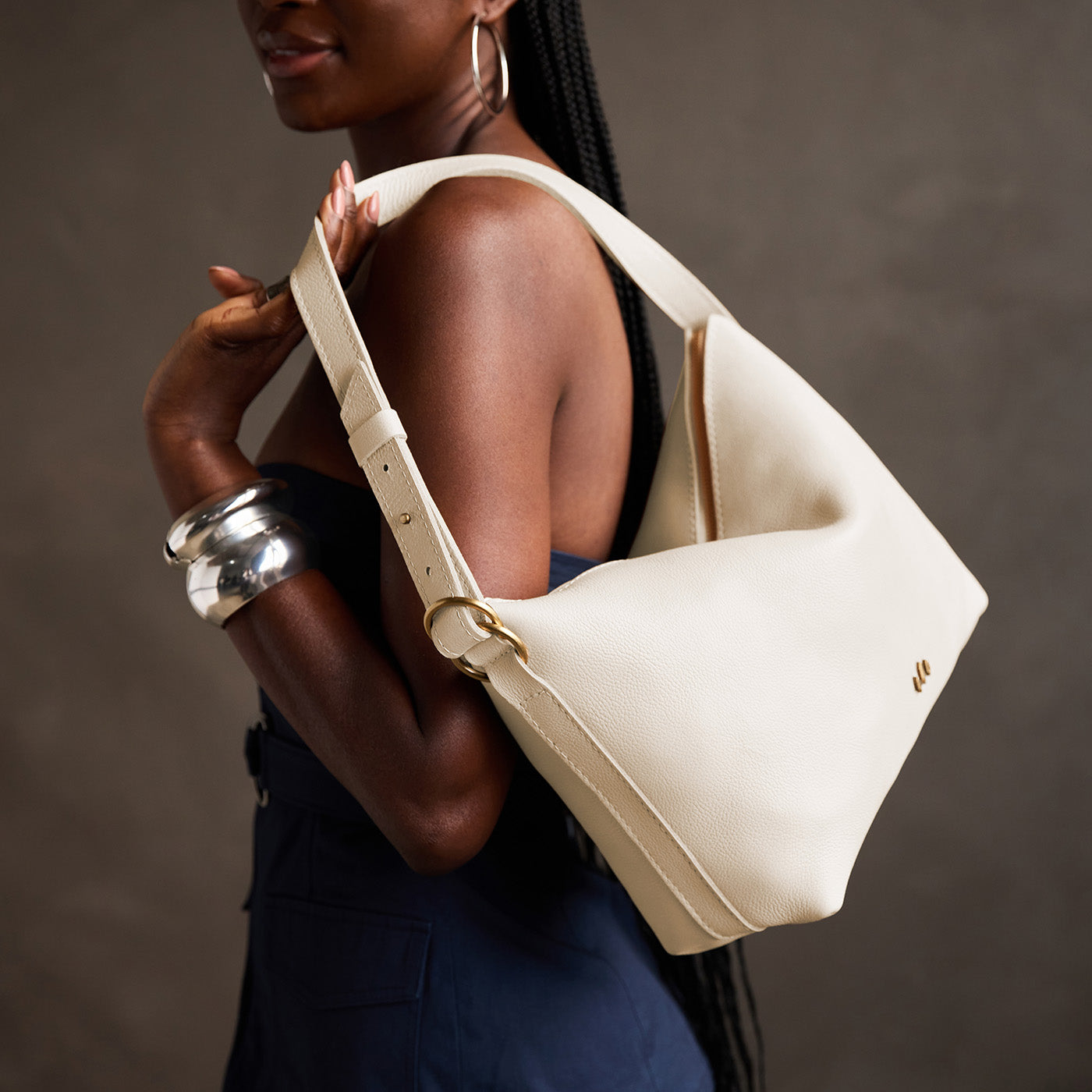 Pebbled Bone*Large | Model Wearing medium sized slouchy leather shoulder bag with zipper opening and three metal tree emblems