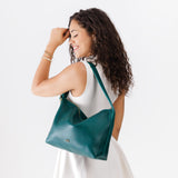 Sea Glass Large | Model wearing medium sized slouchy leather shoulder bag with zipper opening and three metal tree emblems