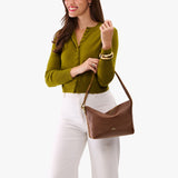 Asheville Small | Model wearing a petite slouchy leather shoulder bag with zipper opening and three metal tree emblems