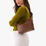 Asheville Small | Model wearing a petite slouchy leather shoulder bag with zipper opening and three metal tree emblems