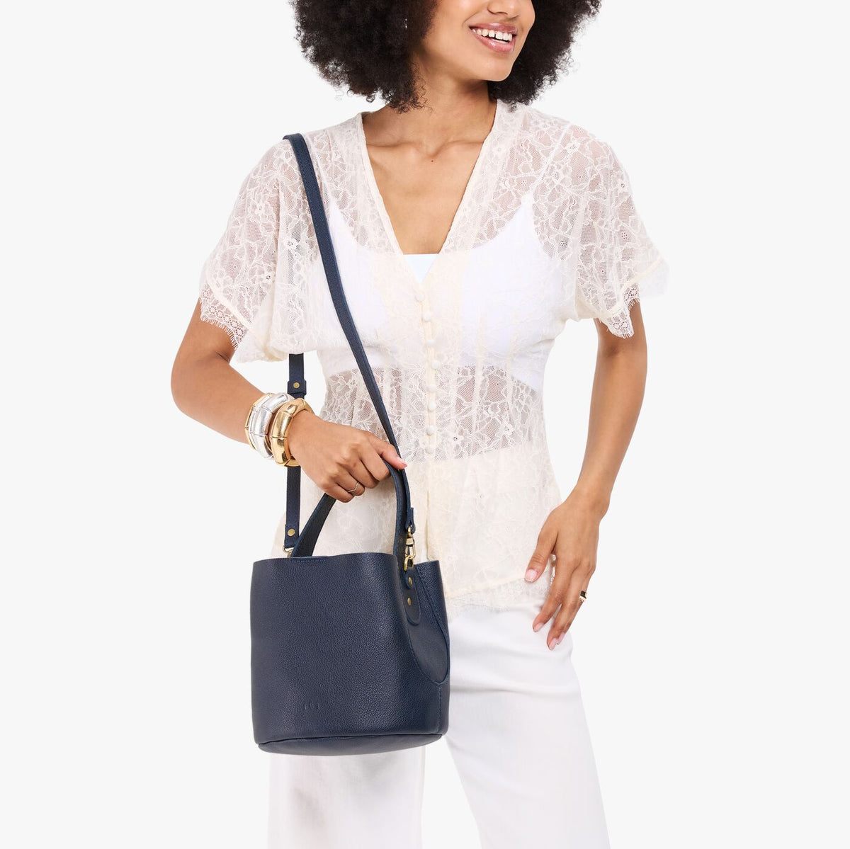Night Owl*Small | Model carrying symmetrical bucket bag with handle, latch closure, and removable crossbody strap