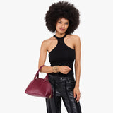 Orchid Small | Model holding a half circle crossbody bag with handles and removable crossbody strap 
