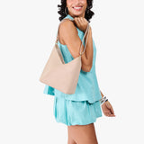 Toasted Oat Small | Model holding petite shoulder bag with adjustable strap and magnetic snap closure
