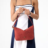 Cinnabar Small | Model holding a Slouchy Shoulder Bag that has a zipper opening and three metal tree emblems