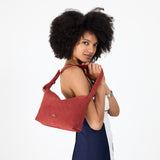 Cinnabar Small | Model holding a Slouchy Shoulder Bag that has a zipper opening and three metal tree emblems