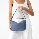 Denim Small | Model holding a Slouchy Shoulder Bag that has a zipper opening and three metal tree emblems