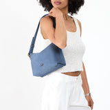Denim Small | Model holding a Slouchy Shoulder Bag that has a zipper opening and three metal tree emblems