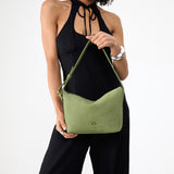 Laurel Small | Model holding a Slouchy Shoulder Bag that has a zipper opening and three metal tree emblems