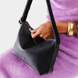 Pebbled--black Small | Model holding petite slouchy leather shoulder bag with zipper opening and three metal tree emblems