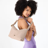 Taupe Small | Model holding a Slouchy Shoulder Bag that has a zipper opening and three metal tree emblems