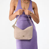 Taupe Small | Model holding a Slouchy Shoulder Bag that has a zipper opening and three metal tree emblems