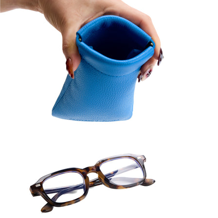 Skydive | Model hand holding open leather glasses case with hidden metal spring closure above a pair of glasses