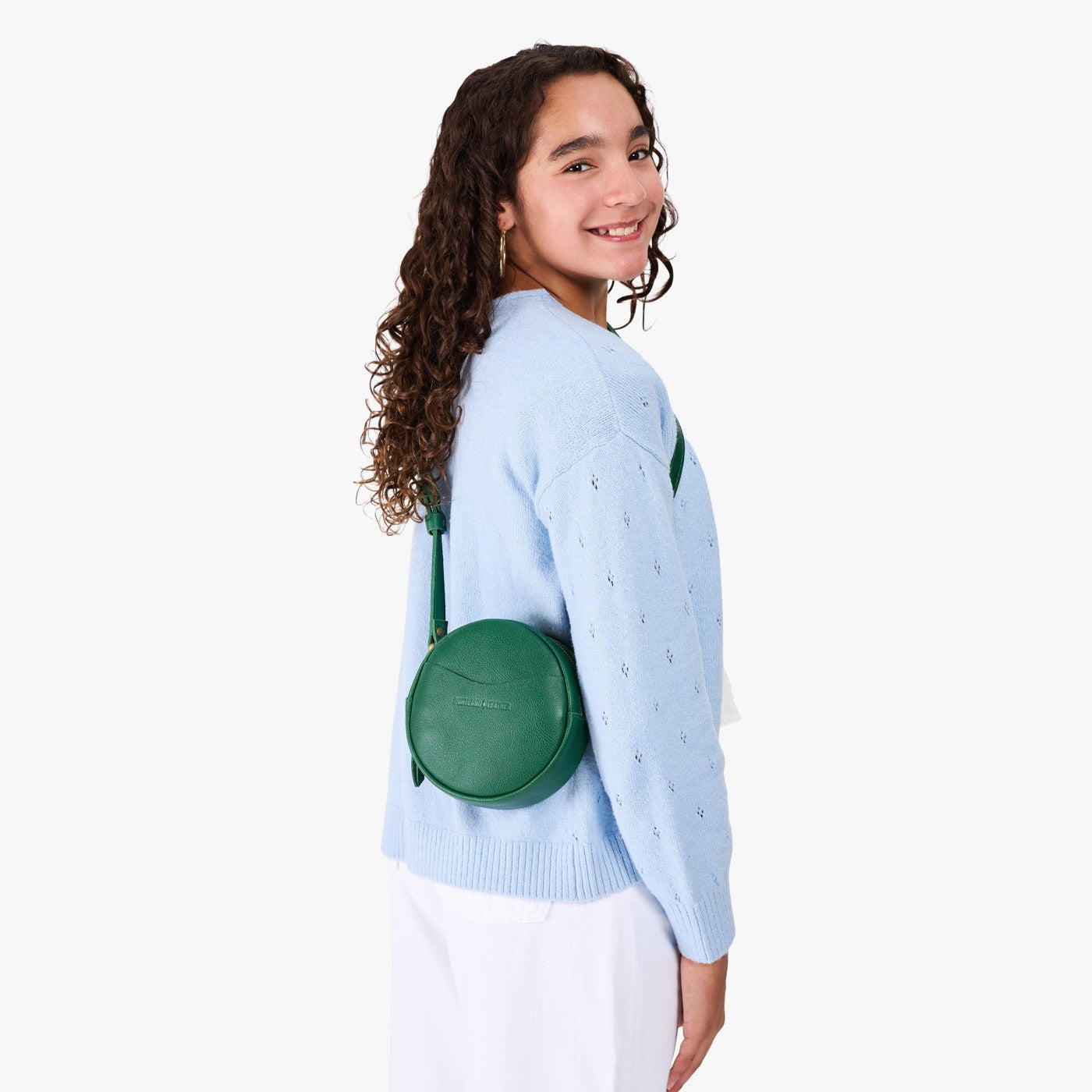Bacalar | Model wearing a circle shaped crossbody bag with top zipper and gold accents