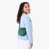 Bacalar | Model wearing a circle shaped crossbody bag with top zipper and gold accents