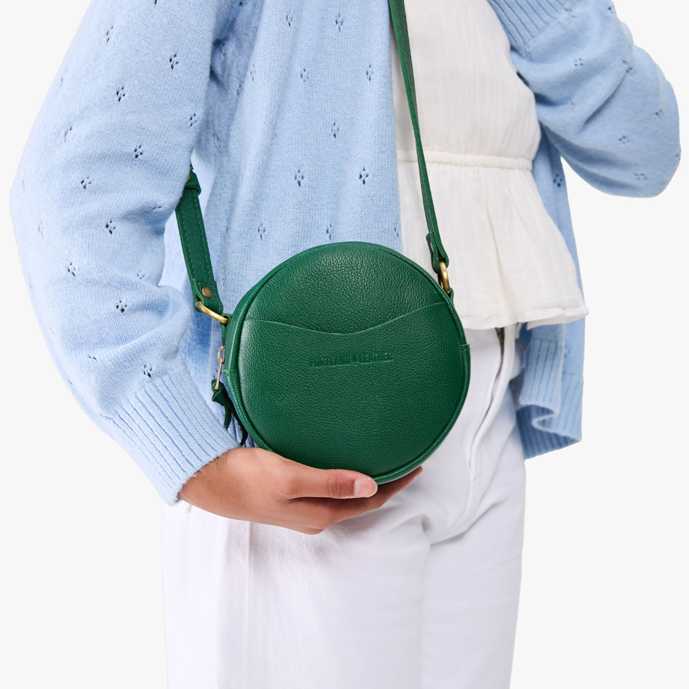 Bacalar | Model wearing a circle shaped crossbody bag with top zipper and gold accents