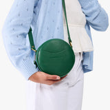 Bacalar | Model wearing a circle shaped crossbody bag with top zipper and gold accents